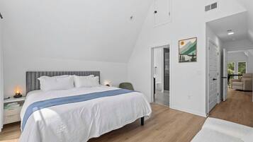 A bedroom with a bed, bedside table, and a nightstand with a lamp.