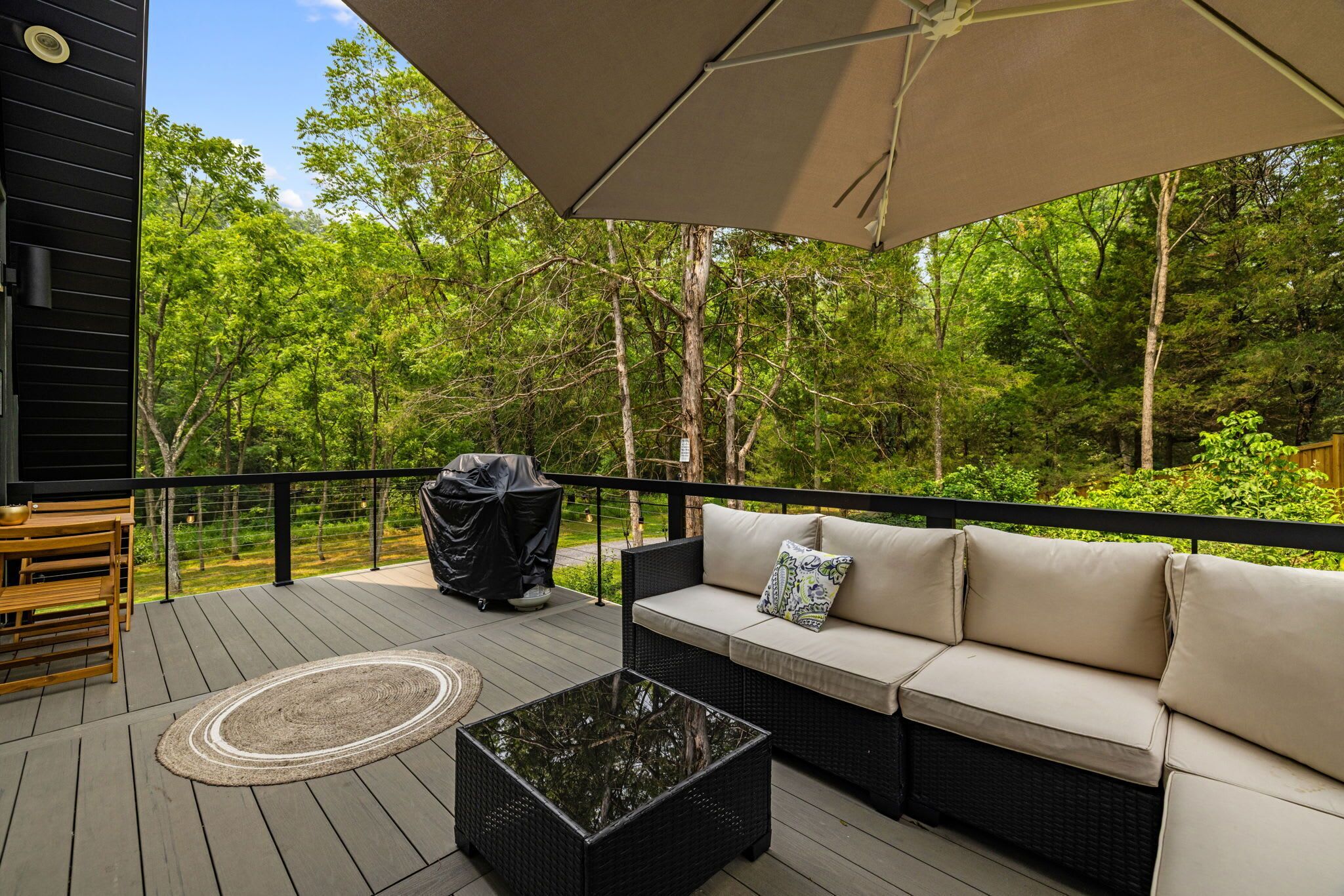 Eine Terrasse mit einer Couch, einem Couchtisch und einem Grill.