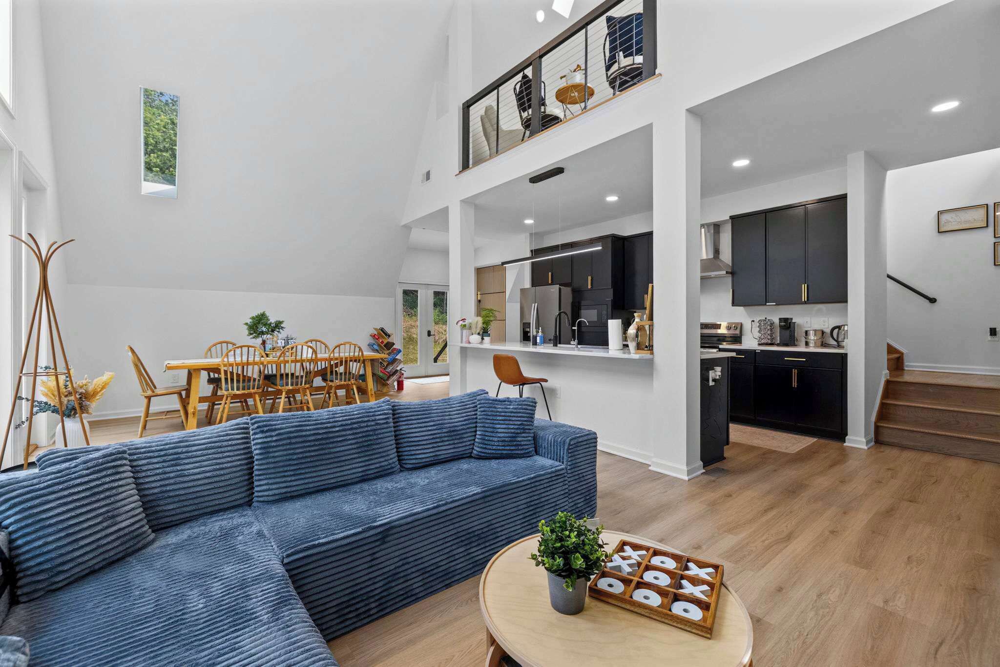 A spacious living area with a sectional sofa, a dining table with chairs, and a kitchen area with dark cabinets and a countertop.
