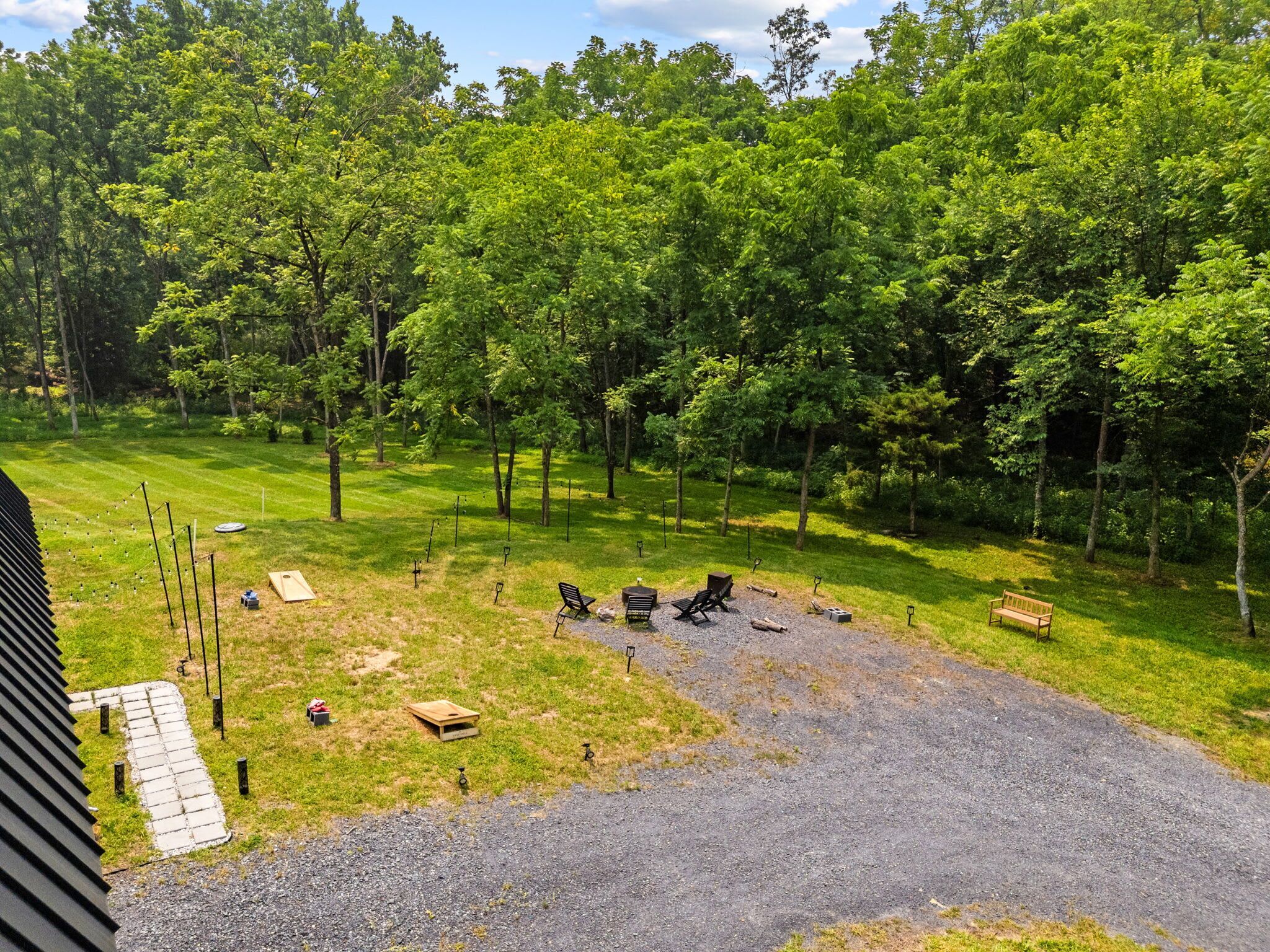 A grassy outdoor area with a gravel path, picnic tables, and benches.
