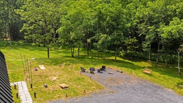 A grassy outdoor area with a gravel path, picnic tables, and benches.