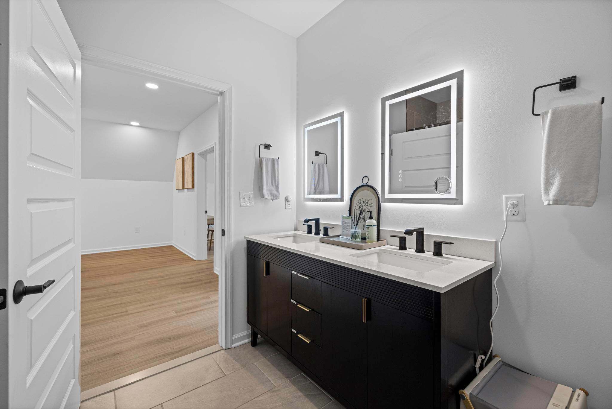 A modern bathroom with a double sink vanity, two wall-mounted mirrors, and a towel rack.