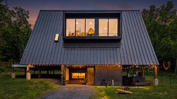 Et moderne hus med et stort vindue, en overdækket veranda og udendørs siddepladser.