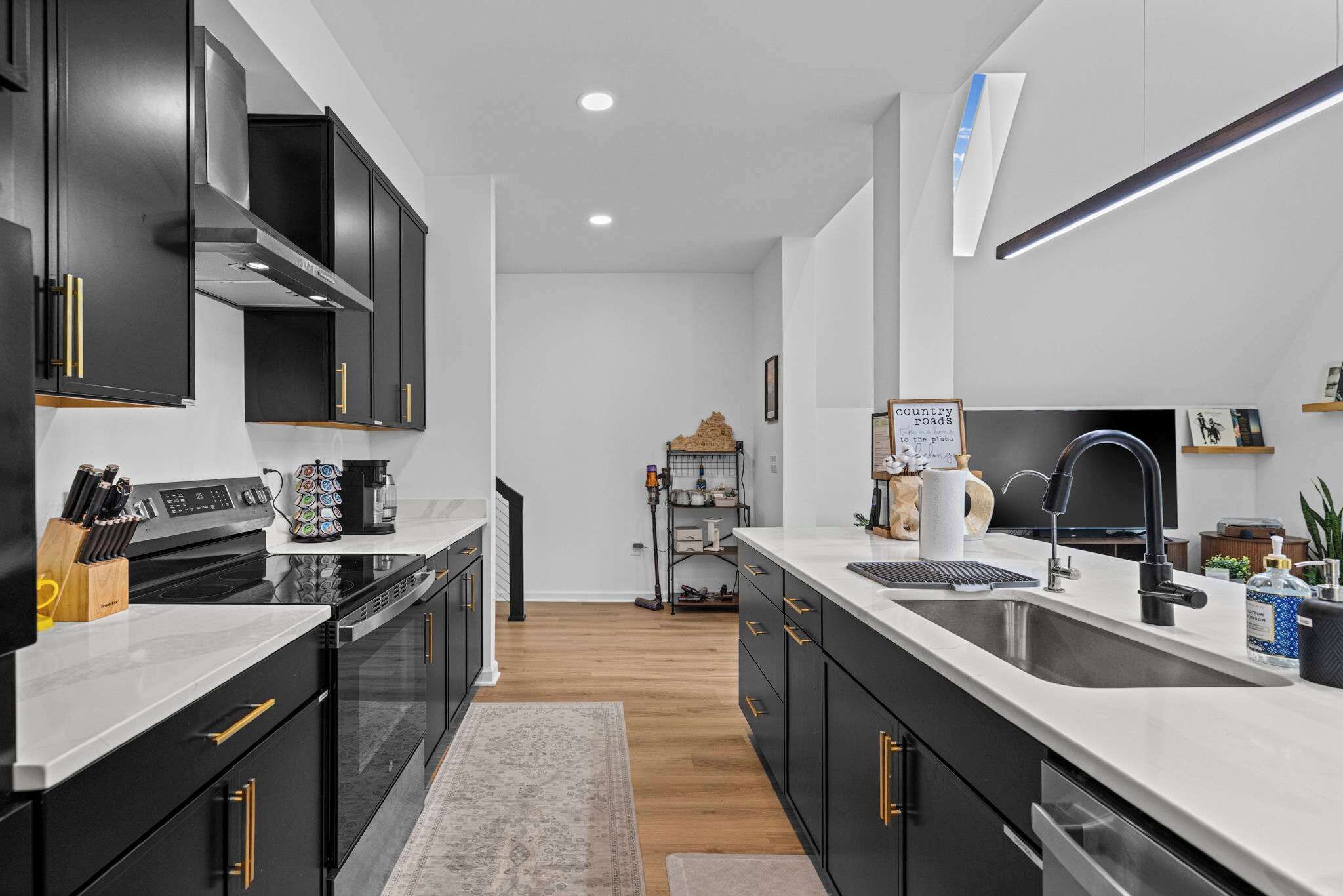 A modern kitchen with black cabinetry, white countertops, and stainless steel appliances.