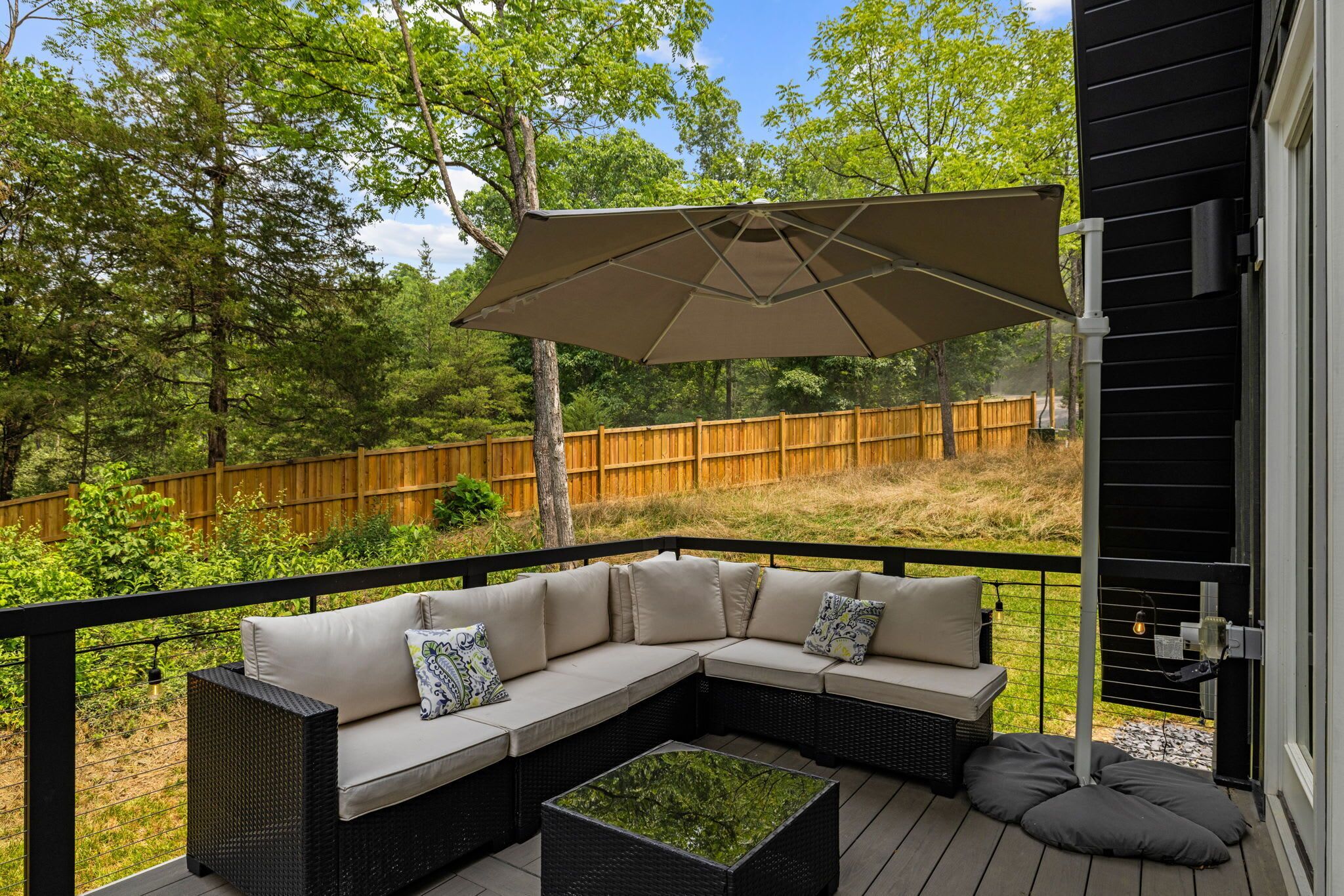 A deck with a sectional sofa, a small table, and a large umbrella.