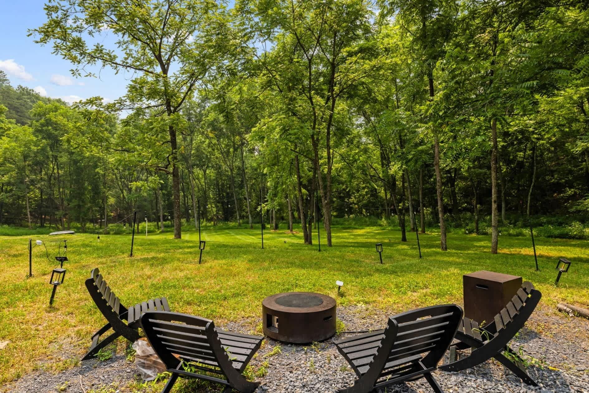 An outdoor seating area with two chairs and a table, surrounded by a forested landscape.