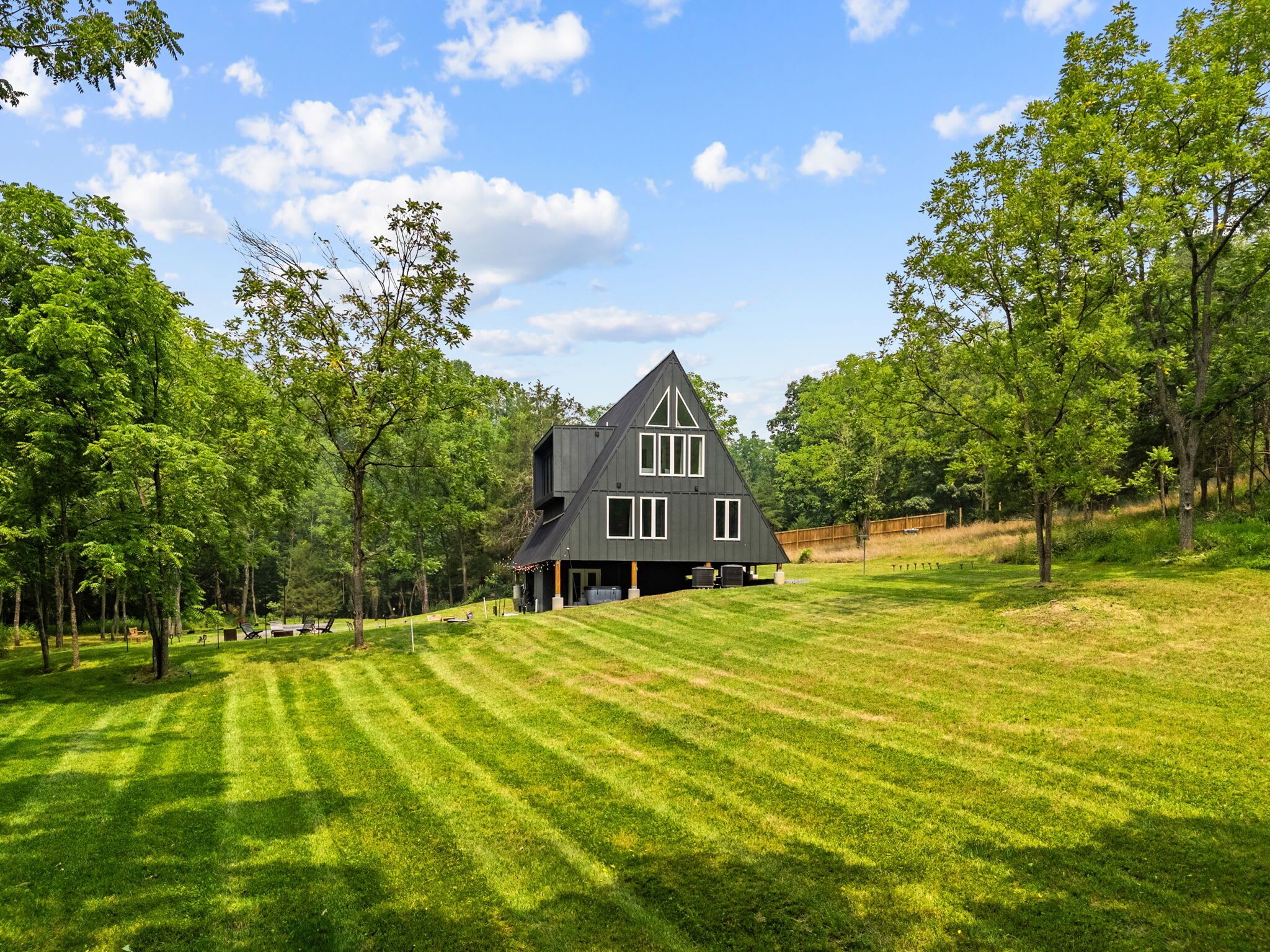 A house with a sloped roof, surrounded by a well-maintained lawn and trees.