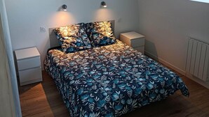 Un dormitorio con una colcha estampada, dos lámparas de noche, una cómoda pequeña y un panel decorativo con motivos geométricos sobre la cama.