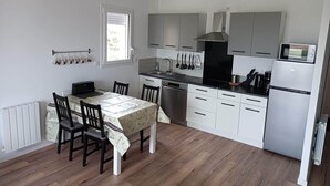 Una cocina compacta con armarios blancos, una estufa negra y un microondas.