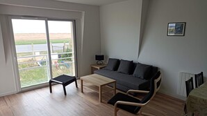 Una sala de estar moderna con un sofá, una mesita, una silla y vistas a través de un ventanal corredero.