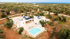 A modern villa with a swimming pool, solar panels, and a view of the surrounding landscape. - Villa delle Stelle by Perle di Puglia (Carovigno)