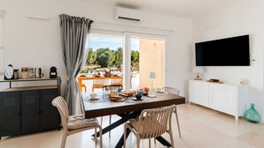 A modern kitchen with a dining area, a TV, and a view of an outdoor pool. - Villa delle Stelle by Perle di Puglia (Carovigno)