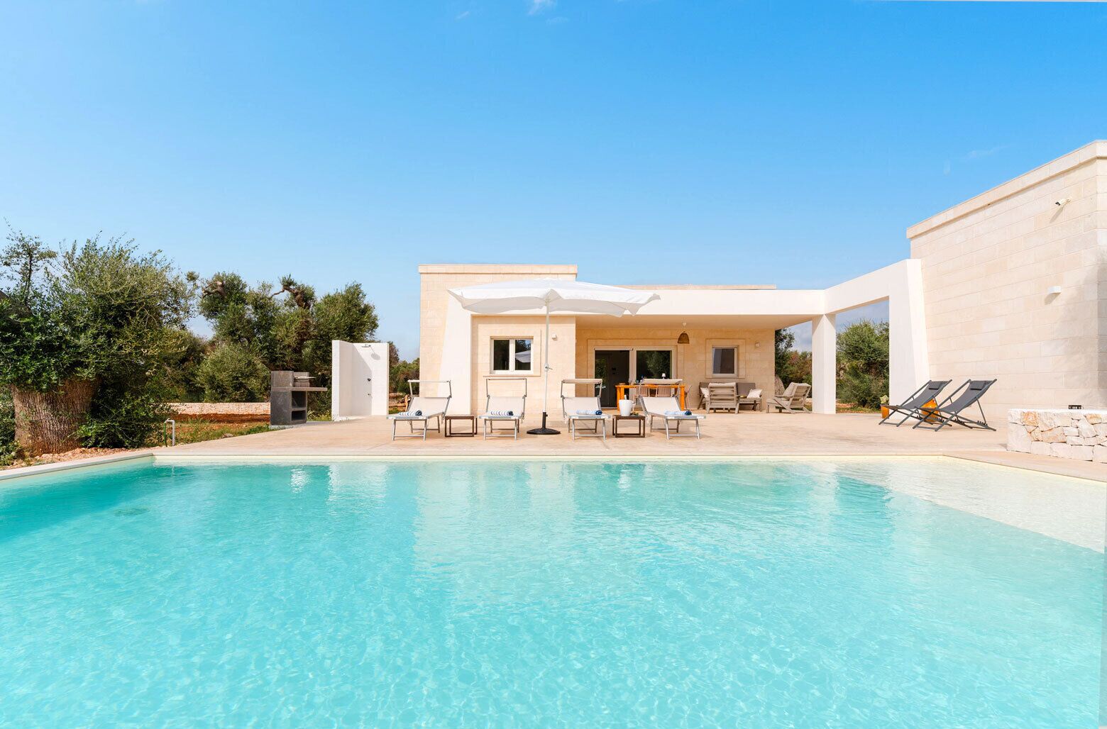 Una casa moderna con piscina, mobiliario de exterior y zona de patio.