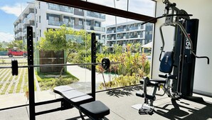 A gym with a bench, weight rack, and exercise equipment. - Makia Beach Resort Luxo - Muro Alto-10 Piscinas (Ipojuca)