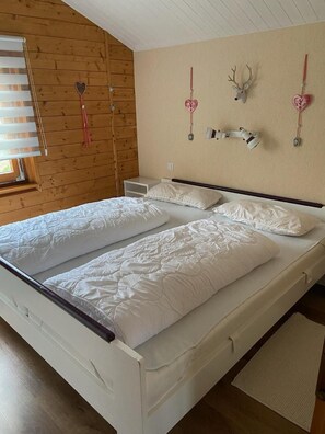 A double bed with white bedding, a wooden headboard, a bedside table, and a wall-mounted deer head decoration. - Chalet 'Blockhaus Ferienzauber 3' with Shared Terrace, Private Garden and Wi-Fi (Allendorf (Eder))