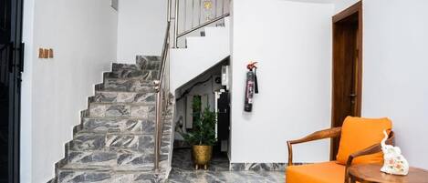 A staircase with marble steps, a wooden chair, a small round table, and a potted plant.