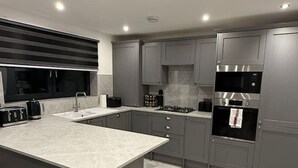 Una cucina moderna con mobili grigi, un'isola grande ed elettrodomestici integrati.