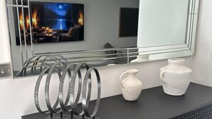 Un interno moderno con uno specchio grande, un mobile nero dalla texture particolare e anelli metallici decorativi.