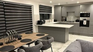Una cucina moderna con mobili grigi, un'isola centrale e un'area pranzo con tavolo in legno e sedie grigie.