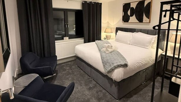 Una camera d'albergo moderna con un letto, una scrivania, una sedia e una finestra con tende.
