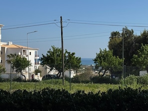 Un quartier résidentiel situé sur la côte, avec un bâtiment blanc, des lignes électriques et une vue dégagée sur la mer.