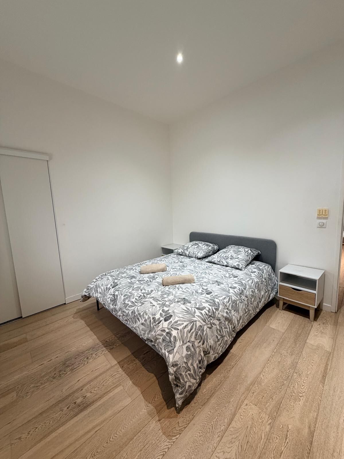 Une chambre à coucher avec un lit, des tables de chevet et une porte.
