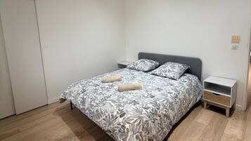 Une chambre à coucher avec un lit, des tables de chevet et une porte.