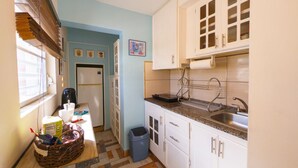 Cocina pequeña con armarios blancos, un lavamanos y un refrigerador.