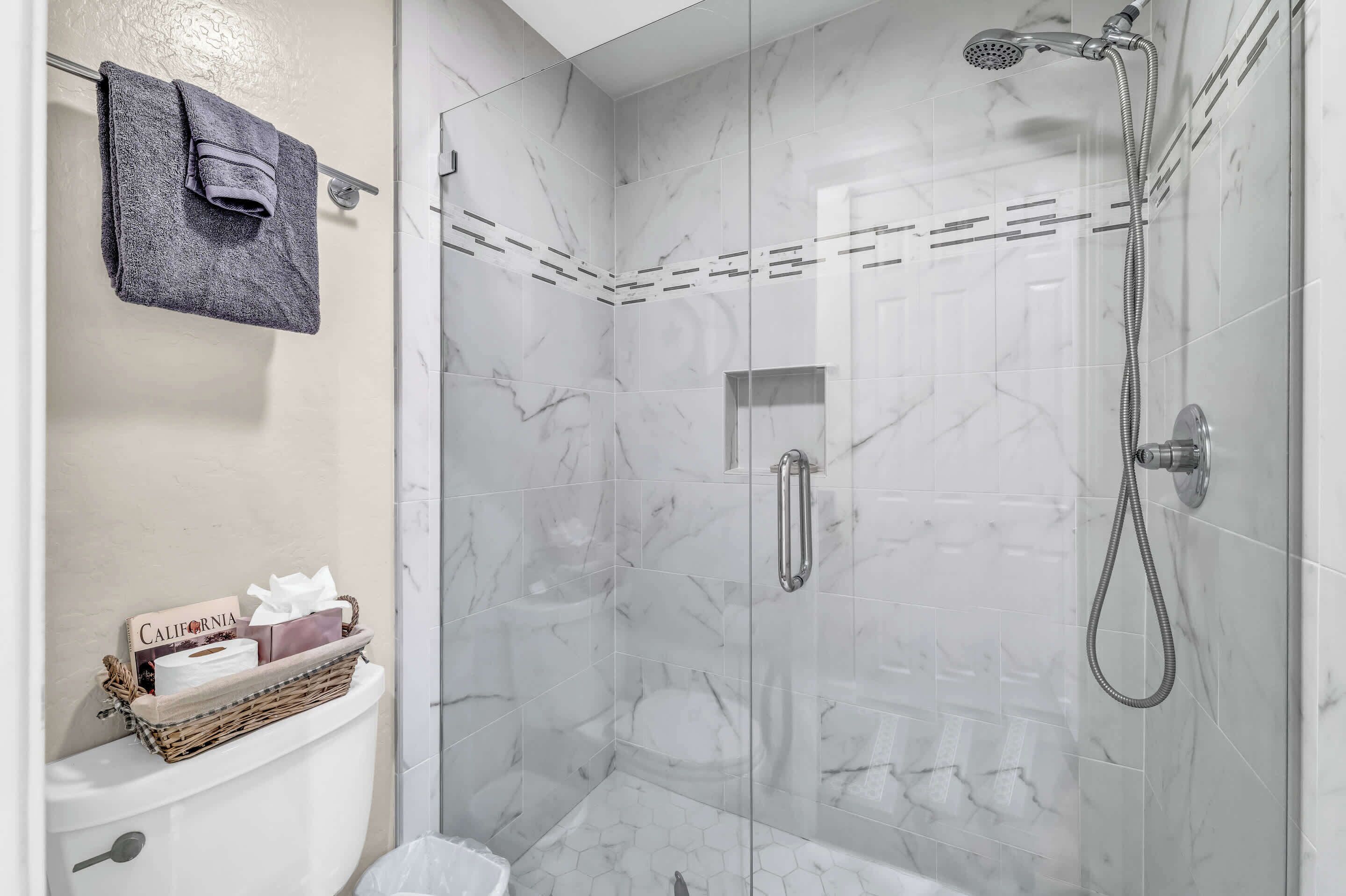 A bathroom with a shower, toilet, and a towel rack.