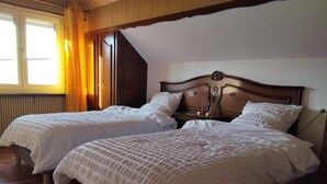 Een kamer met twee bedden, houten hoofdeinden en een raam met gordijnen.