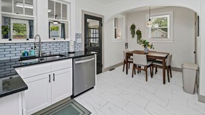 A kitchen with white cabinets, a black countertop, and a dining table with chairs. - 4BR Retreat w/ Game Shed | Near Downtown (West Columbia)