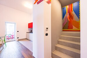 A modern interior with a staircase, a kitchen area, and a colorful wall mural. - Wide and Arty at Spanish Quarter (Naples)