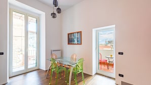 A modern interior with a glass table and chairs, a radiator, and a framed picture on the wall. - Wide and Arty at Spanish Quarter (Naples)