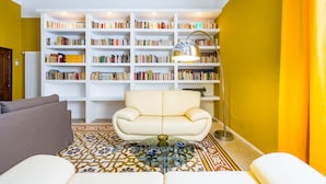 A living room with a sofa, a glass coffee table, a patterned rug, a bookshelf, and a lamp. - Wide and Arty at Spanish Quarter (Naples)