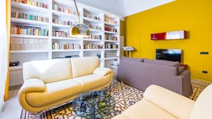 A living room with a sofa, a coffee table, a bookshelf, and a TV. - Wide and Arty at Spanish Quarter (Naples)