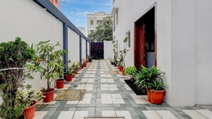 A narrow alleyway with potted plants on either side, leading to a building entrance. - Deluxe k.k Nagar Residency (Chennai)