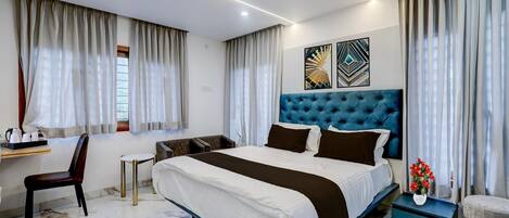 A modern bedroom with a large bed, a desk, a chair, and a small table.