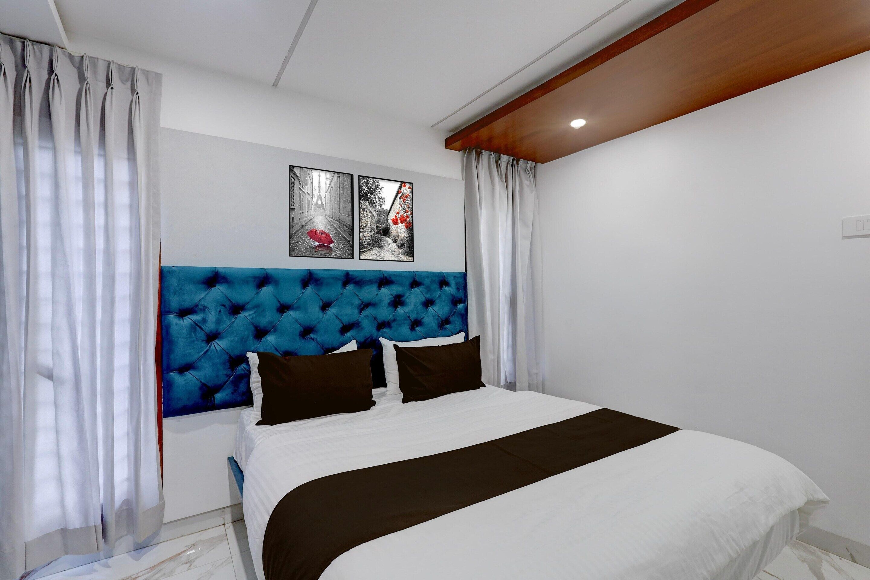 A bedroom with a tufted headboard, a bed with white and brown bedding, and two framed pictures on the wall.