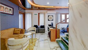 A hotel lobby with a reception desk, seating area, staircase, and artwork on the walls. - Deluxe k.k Nagar Residency (Chennai)