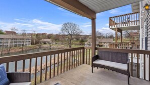 Un espace extérieur abrité avec vue sur une rivière, une terrasse en bois et un balcon au deuxième étage.