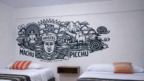 Una camera d'albergo con due letti, un affresco sulla parete e un pavimento in legno.