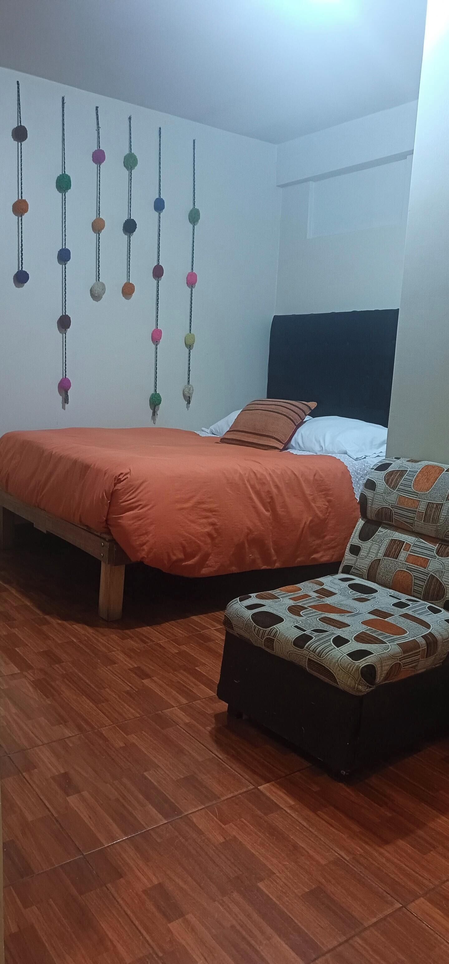 Un dormitorio con cama, una silla y un adorno en la pared.