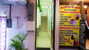 L'ingresso di un ristorante con un cartello che elenca bevande calde e fredde, una pianta in vaso e il numero 113 sulla porta.