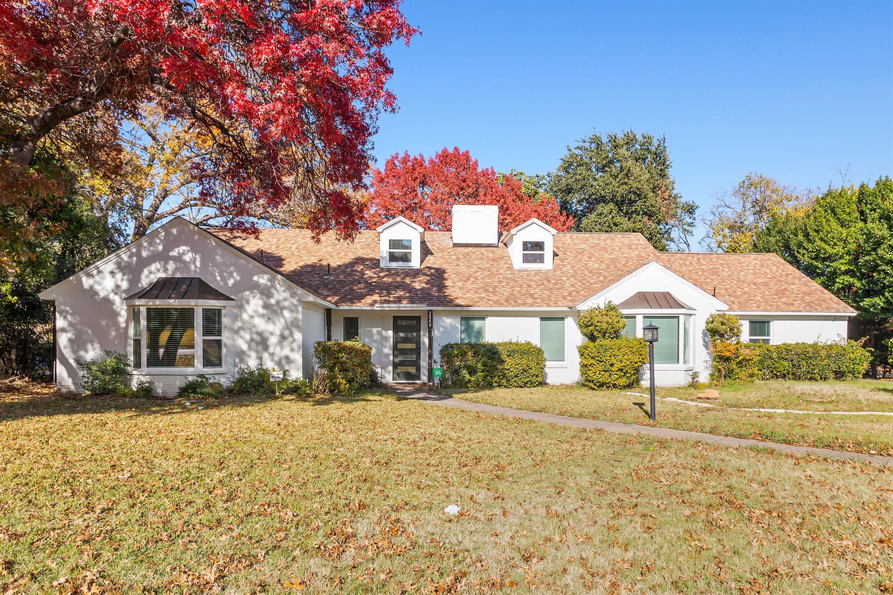 A two-story house with a front porch, a garage, and a well-maintained lawn.