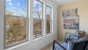 A room with three large windows, a view of trees, and a wall with a 'Lake Rules' sign. - Luxury Lake Vacation at Emerald Pointe (Hollister)