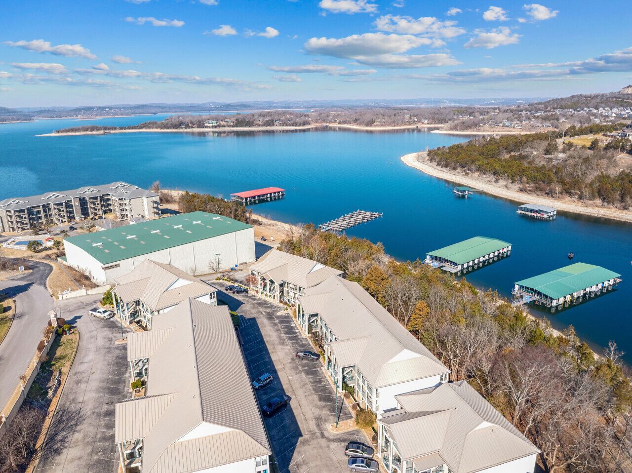 An aerial view of a waterfront property with multiple buildings, a parking lot, and a dock area.