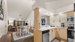 A modern kitchen with a dishwasher, oven, and coffee maker. - Luxury Lake Vacation at Emerald Pointe (Hollister)