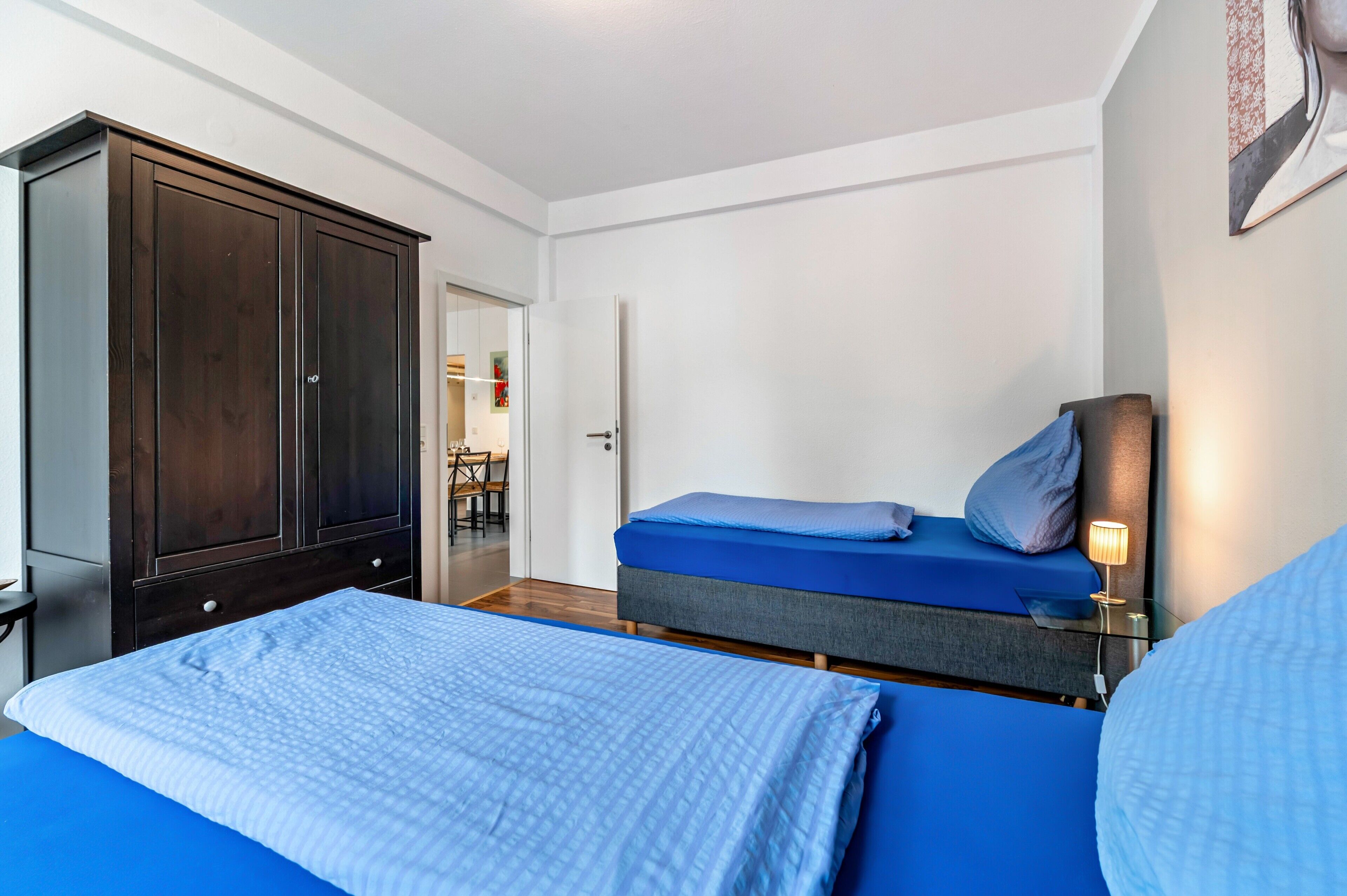 A bedroom with a bed, a wardrobe, and a bedside lamp.