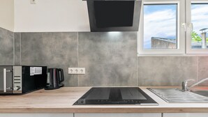 A modern kitchen with a built-in induction cooktop, a kettle, and a sink. - Ideal for Contractors: 2 Bedrooms for 4 Guests (65 m²) in Saarbrücken, Free Parking (Saarbrücken)