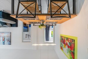 Un interior moderno con techo de madera, obra de arte enmarcadas y ventana con cortinas.